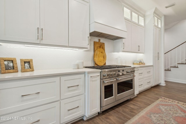 kitchen featuring range with two ovens, backsplash, white cabinetry, custom exhaust hood, and dark wood-type flooring