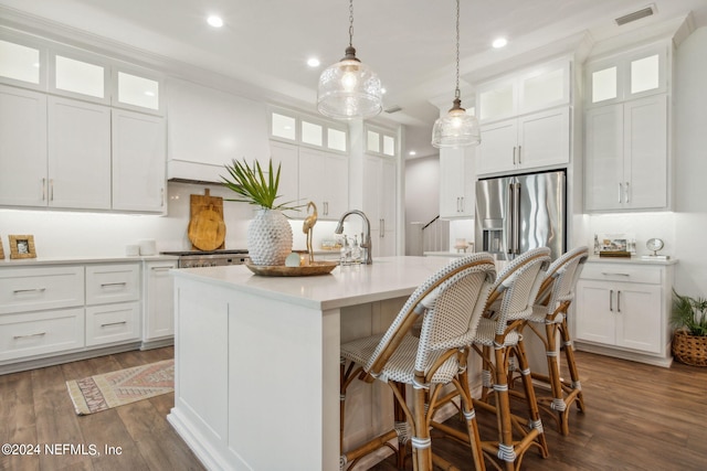 kitchen with high end fridge, a center island with sink, and white cabinets