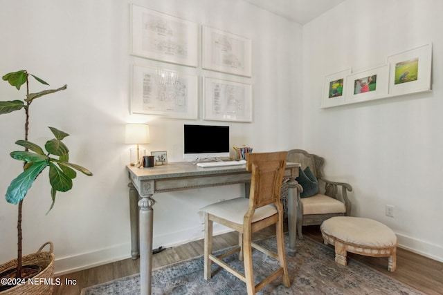 home office with built in desk and dark hardwood / wood-style flooring