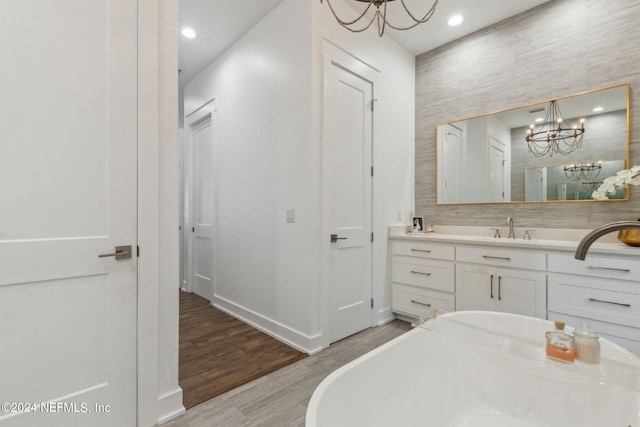 bathroom featuring vanity, hardwood / wood-style floors, a tub, and an inviting chandelier