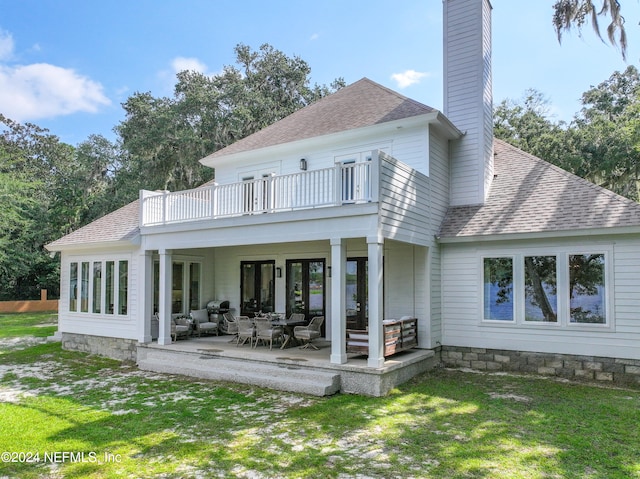 rear view of house with a patio area, a yard, and a balcony