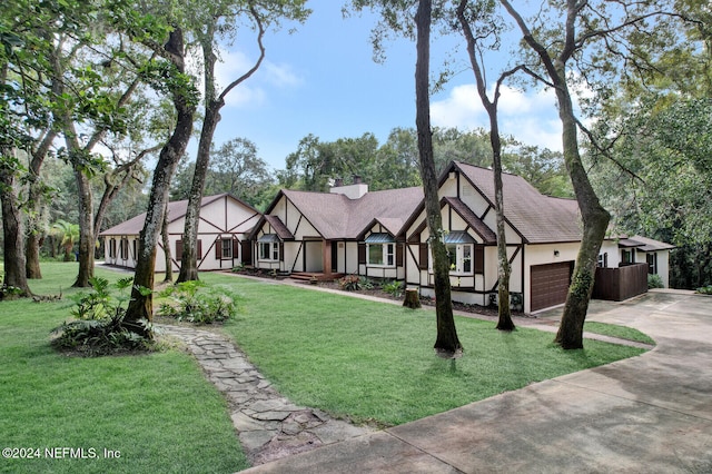 tudor-style house featuring a front yard and a garage