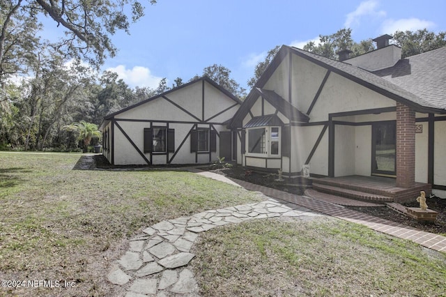 3565 Red Cloud Trl, Saint Augustine, FL 32086 - back of property featuring a lawn, a chimney, stucco siding, and roof with shingles