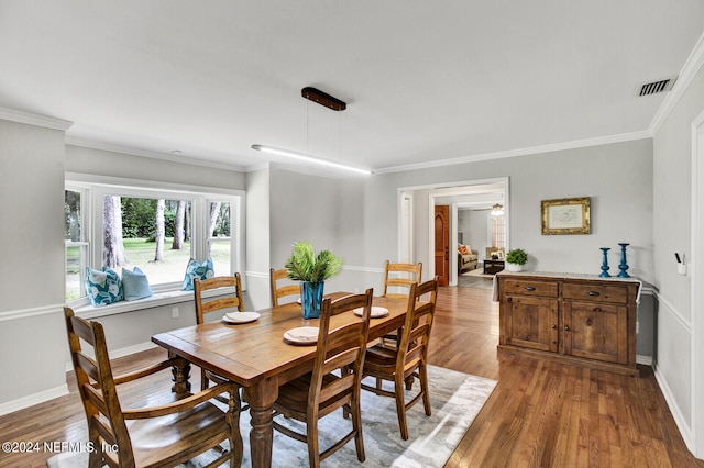 dining space featuring ornamental molding and light hardwood / wood-style flooring