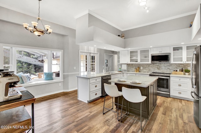 3565 Red Cloud Trl, Saint Augustine, FL 32086 - kitchen with white cabinets, stainless steel appliances, a peninsula, a sink, and wood finished floors