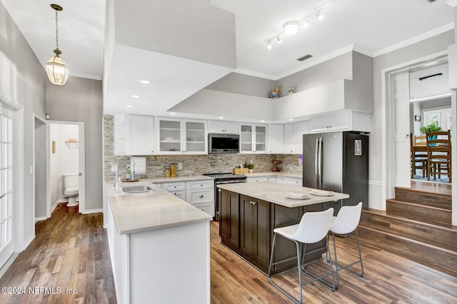 kitchen with appliances with stainless steel finishes, sink, a center island, white cabinetry, and dark hardwood / wood-style floors