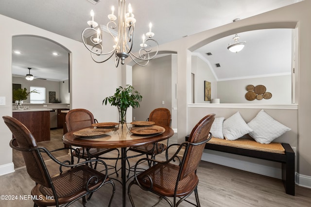 dining space with hardwood / wood-style flooring, ornamental molding, vaulted ceiling, and ceiling fan with notable chandelier