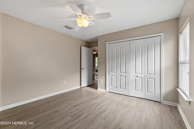 unfurnished bedroom with light hardwood / wood-style flooring, a textured ceiling, a closet, and ceiling fan