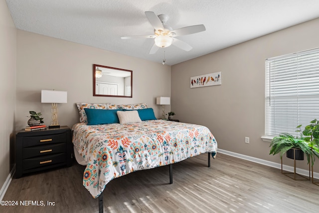 bedroom with ceiling fan, wood-type flooring, and a textured ceiling