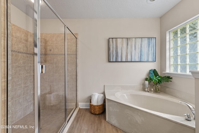 bathroom featuring a textured ceiling, plus walk in shower, and wood-type flooring