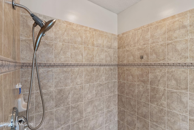 bathroom with a textured ceiling and tiled shower