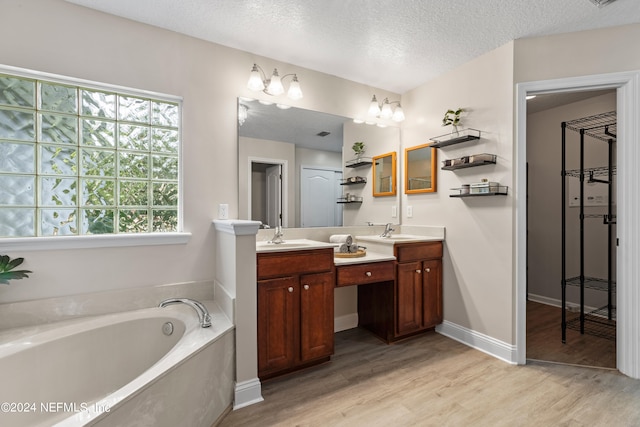 bathroom with vanity, a tub to relax in, hardwood / wood-style flooring, and a textured ceiling