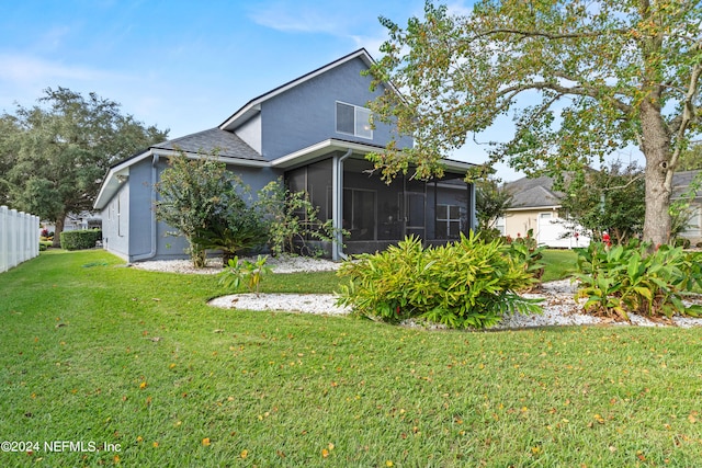 back of property with a sunroom and a lawn