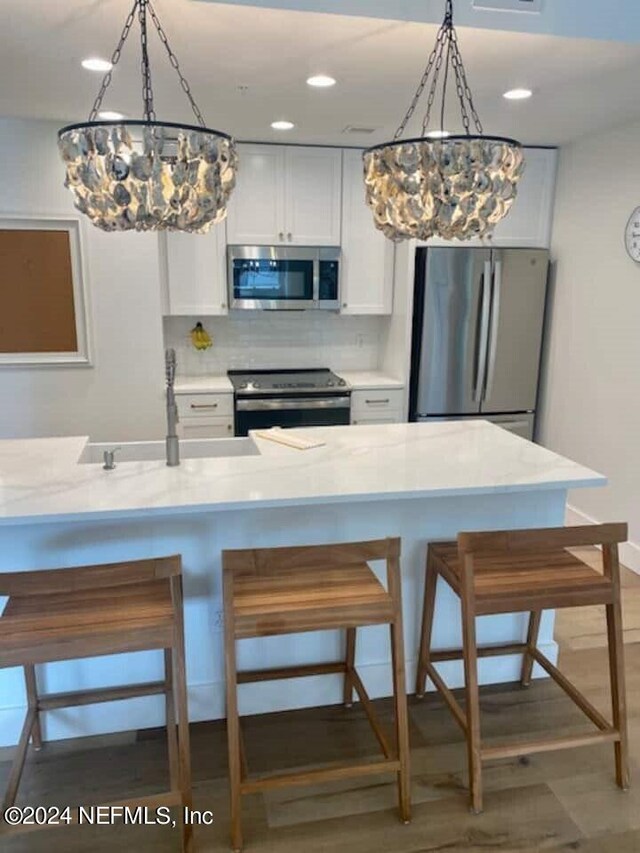 kitchen with decorative light fixtures, appliances with stainless steel finishes, backsplash, and white cabinets