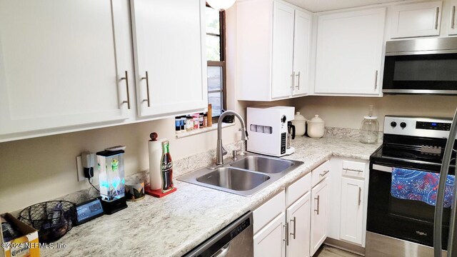 kitchen with white cabinets, light stone counters, appliances with stainless steel finishes, and sink