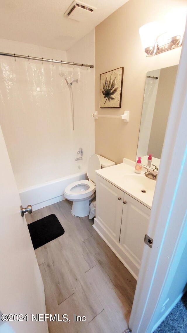 full bathroom featuring shower / bath combo, hardwood / wood-style flooring, vanity, and toilet