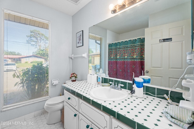 bathroom featuring a textured ceiling, walk in shower, toilet, vanity, and tile patterned floors