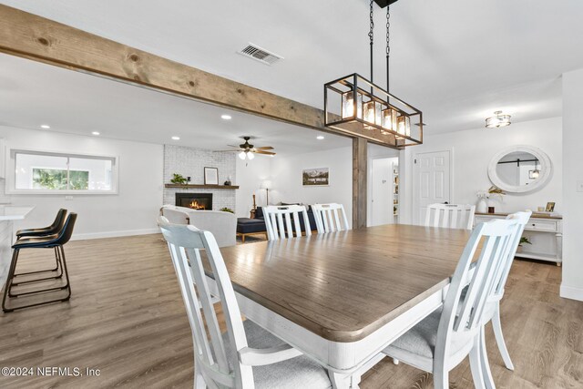 dining space featuring ceiling fan, hardwood / wood-style flooring, and a fireplace