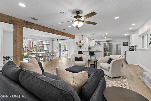 living room featuring light hardwood / wood-style floors, ceiling fan, and a textured ceiling