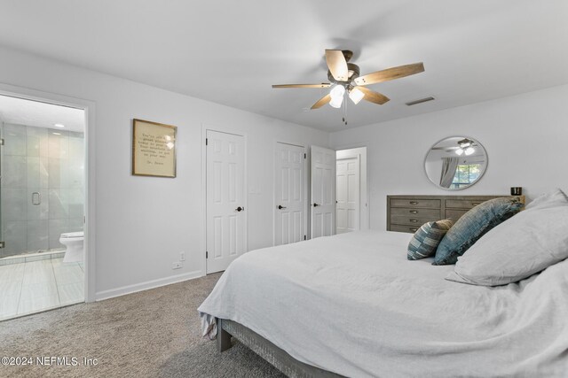 carpeted bedroom featuring multiple closets, ceiling fan, and ensuite bathroom