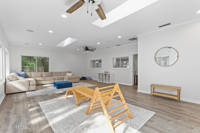 living room with hardwood / wood-style floors, a skylight, and ceiling fan