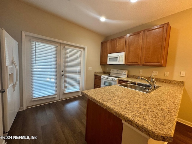 kitchen with kitchen peninsula, sink, white appliances, a textured ceiling, and dark wood-type flooring