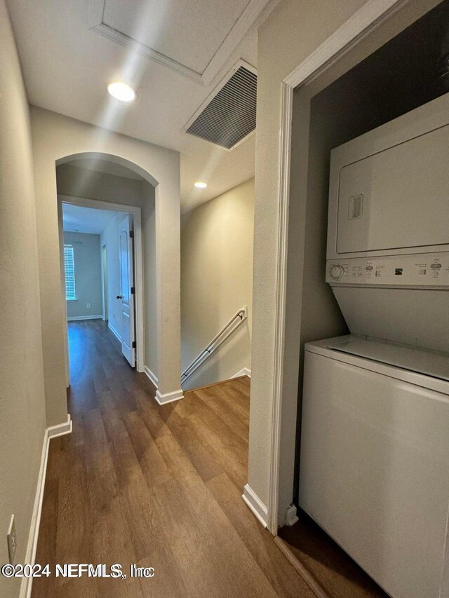 laundry area with wood-type flooring and stacked washing maching and dryer