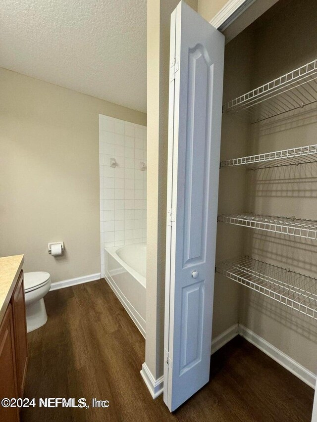 full bathroom with a textured ceiling, hardwood / wood-style flooring, vanity, and toilet