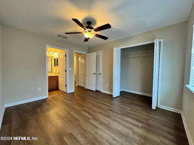 unfurnished bedroom featuring a textured ceiling, dark hardwood / wood-style floors, ceiling fan, and ensuite bath