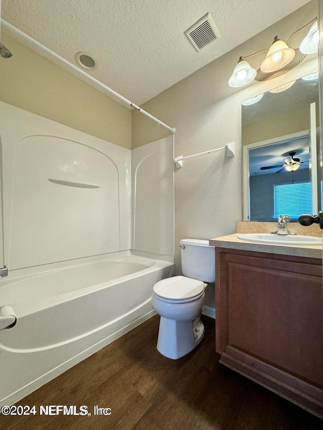 full bathroom featuring vanity, wood-type flooring, tub / shower combination, a textured ceiling, and toilet