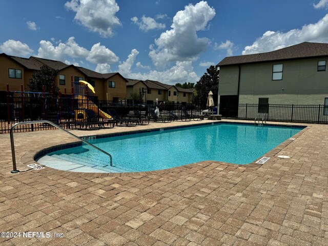 view of swimming pool featuring a patio and a playground