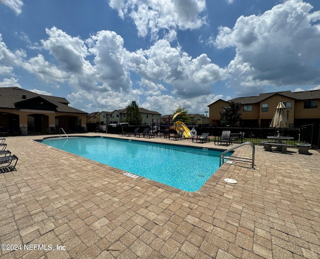 view of pool featuring a playground and a patio