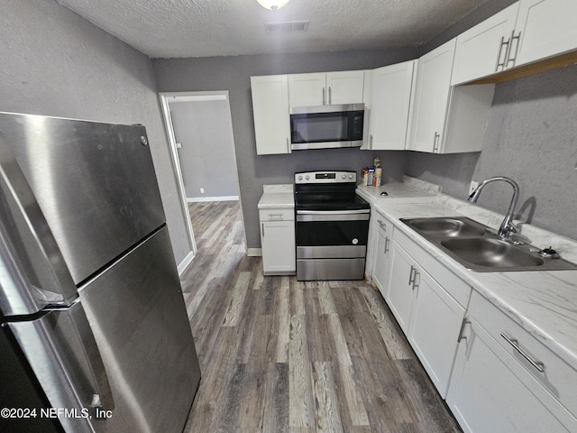 1359 W 22nd St, Jacksonville, FL 32209 - kitchen with stainless steel appliances, dark wood-style floors, a textured ceiling, white cabinets, and a textured wall