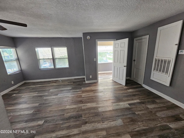 empty room with ceiling fan, a textured ceiling, and dark hardwood / wood-style flooring