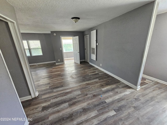 interior space with a textured ceiling and dark hardwood / wood-style flooring