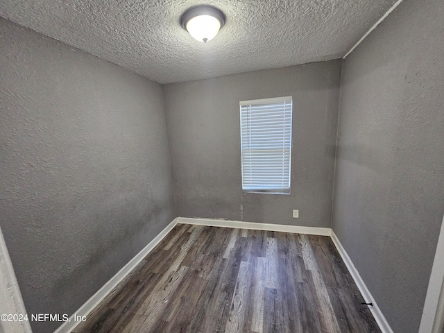 unfurnished room featuring a textured ceiling and dark hardwood / wood-style flooring