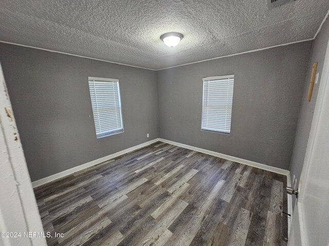 empty room with dark wood-type flooring and a textured ceiling