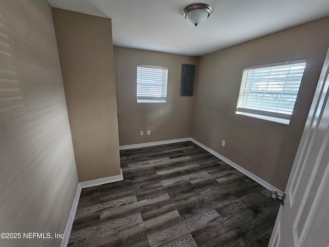 unfurnished room featuring electric panel, dark hardwood / wood-style floors, and a healthy amount of sunlight