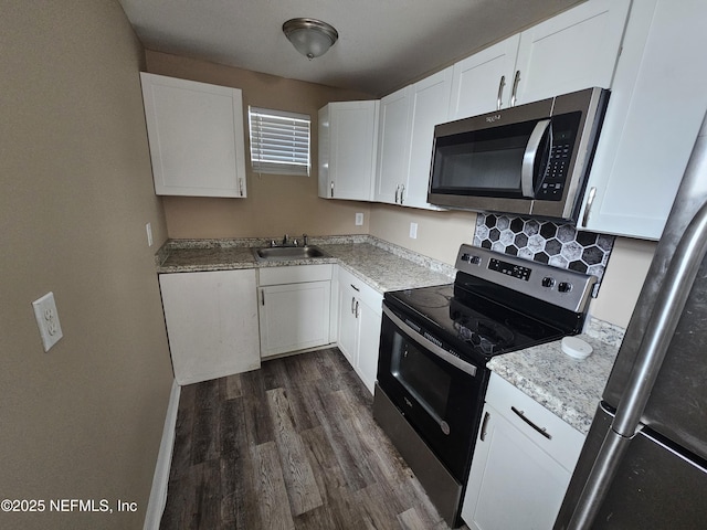 kitchen with white cabinets, stainless steel appliances, sink, dark hardwood / wood-style floors, and light stone counters