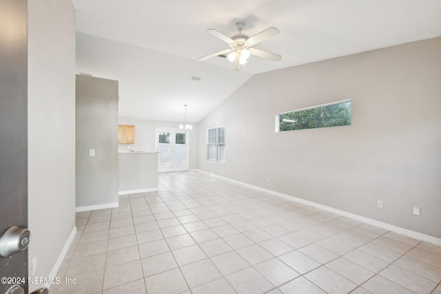 empty room featuring light tile patterned floors, ceiling fan with notable chandelier, and a wealth of natural light