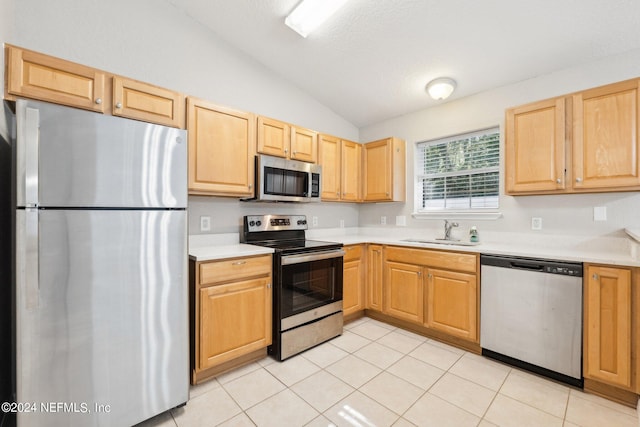 kitchen featuring appliances with stainless steel finishes, sink, lofted ceiling, light tile patterned floors, and light brown cabinets