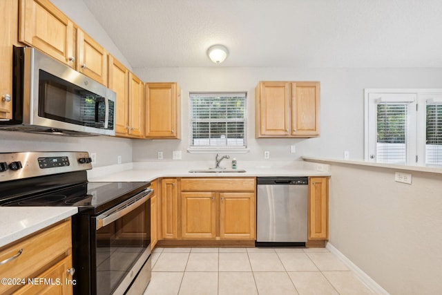 kitchen featuring light tile patterned flooring, a healthy amount of sunlight, stainless steel appliances, and sink