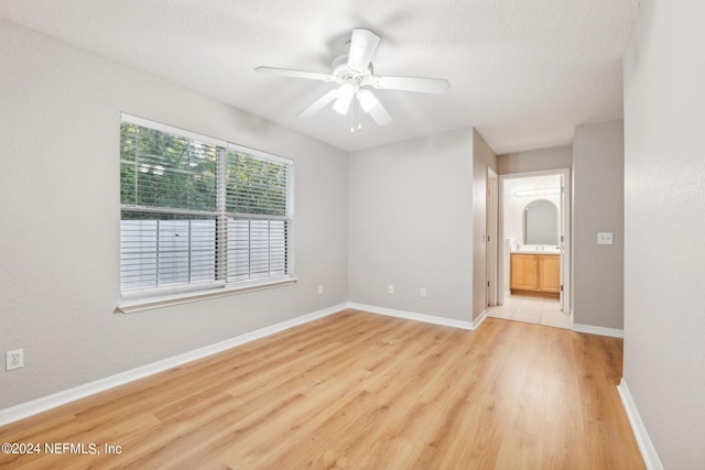 spare room with a textured ceiling, light wood-type flooring, and ceiling fan