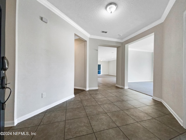 tiled empty room with a textured ceiling and ornamental molding