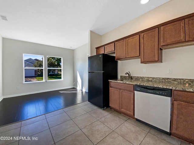 kitchen featuring sink, stone countertops, stainless steel dishwasher, light wood-type flooring, and black refrigerator