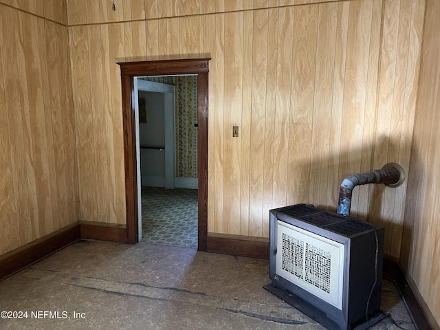 interior space featuring wood walls, heating unit, and a wood stove