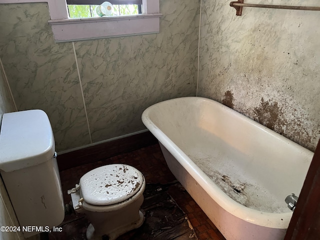 bathroom with a tub to relax in and toilet