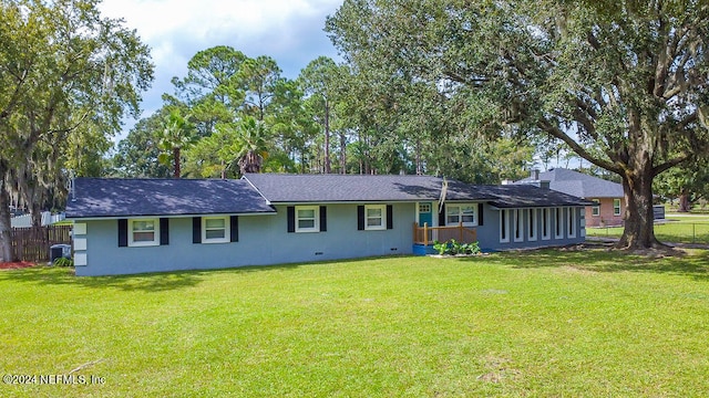 rear view of property with central AC unit and a lawn