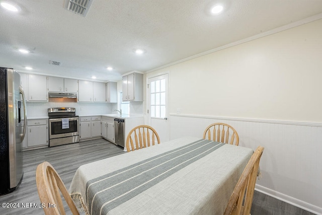 dining space featuring light wood-type flooring, crown molding, and sink