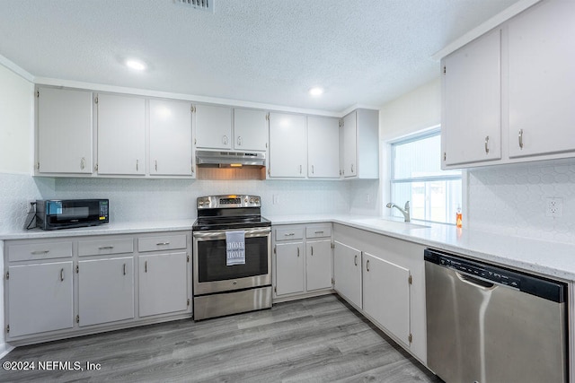 kitchen featuring white cabinets, appliances with stainless steel finishes, sink, and light hardwood / wood-style flooring